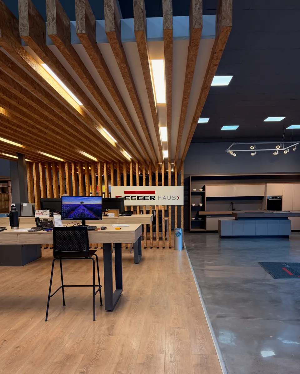 Interior del espacio Egger Haus, con cielorraso de listones de madera y puestos de atención.